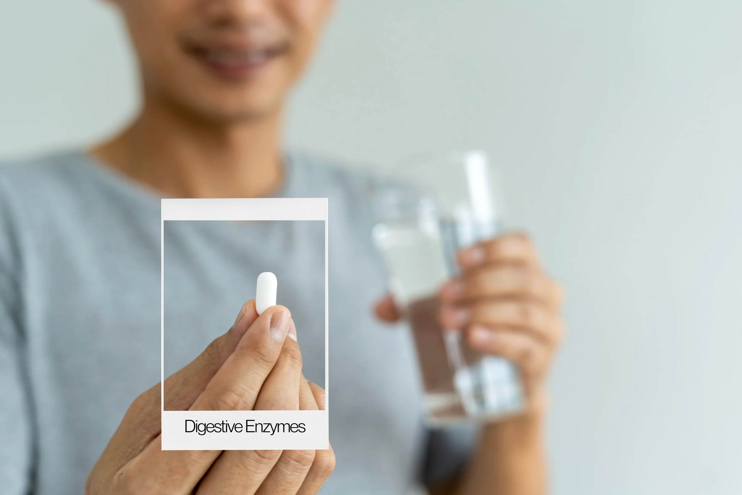 Man in blue shirt holding a pill in one hand and a glass of water in the other