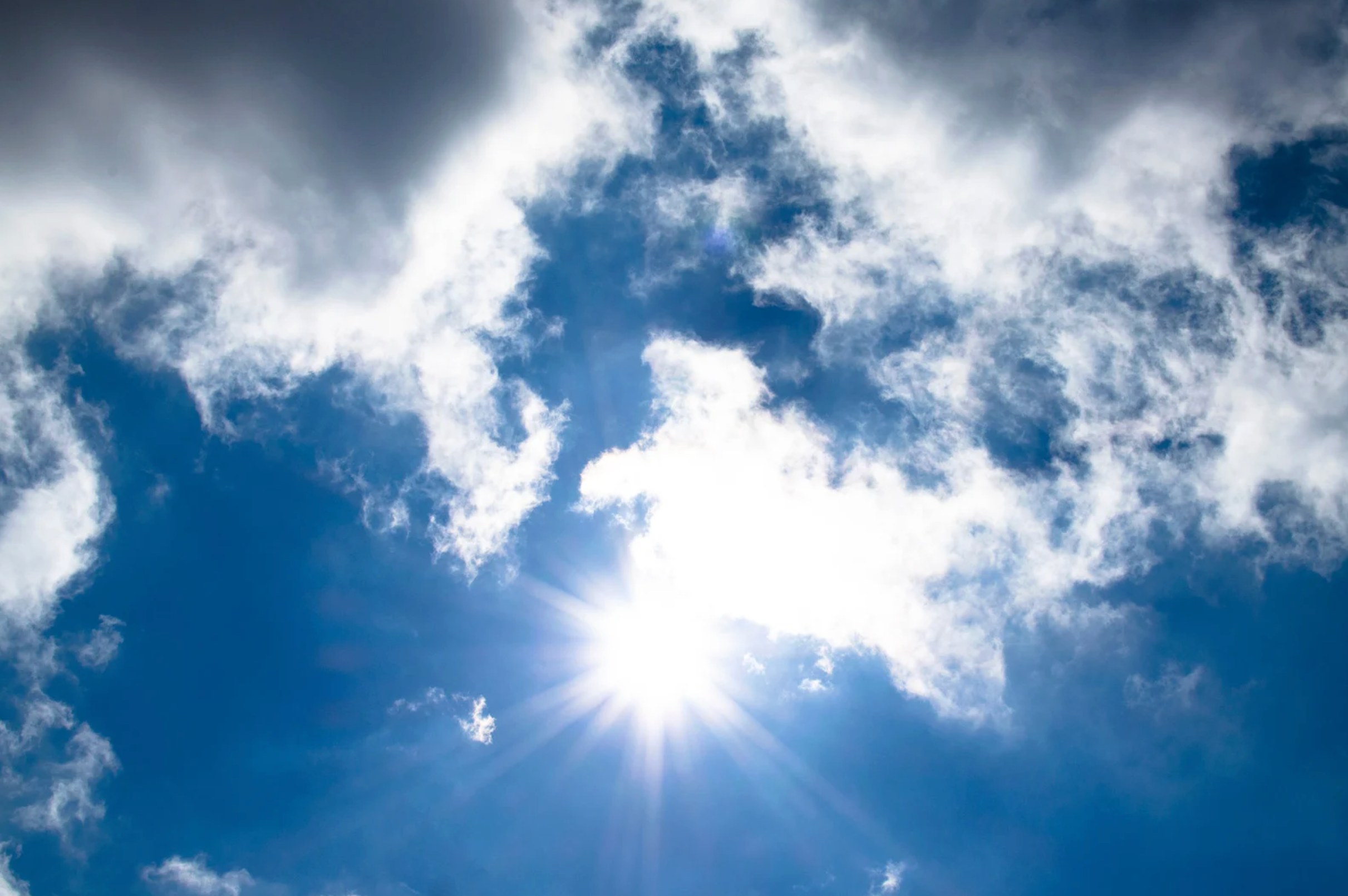Blue sky with the sun partially blocked by clouds