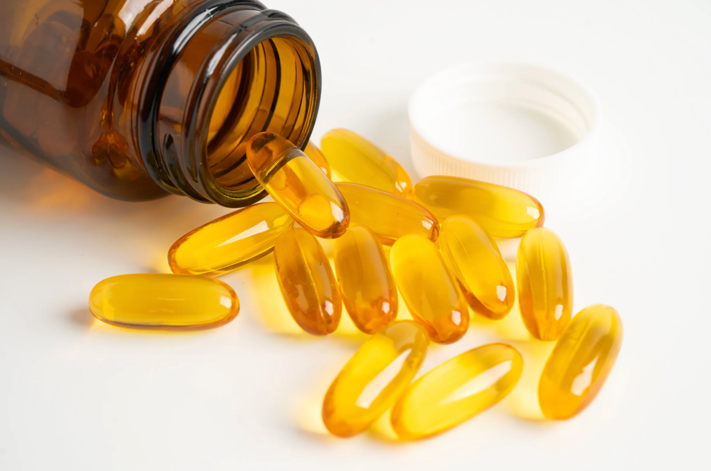 Open brown supplement bottle with fish oil softgels pouring out