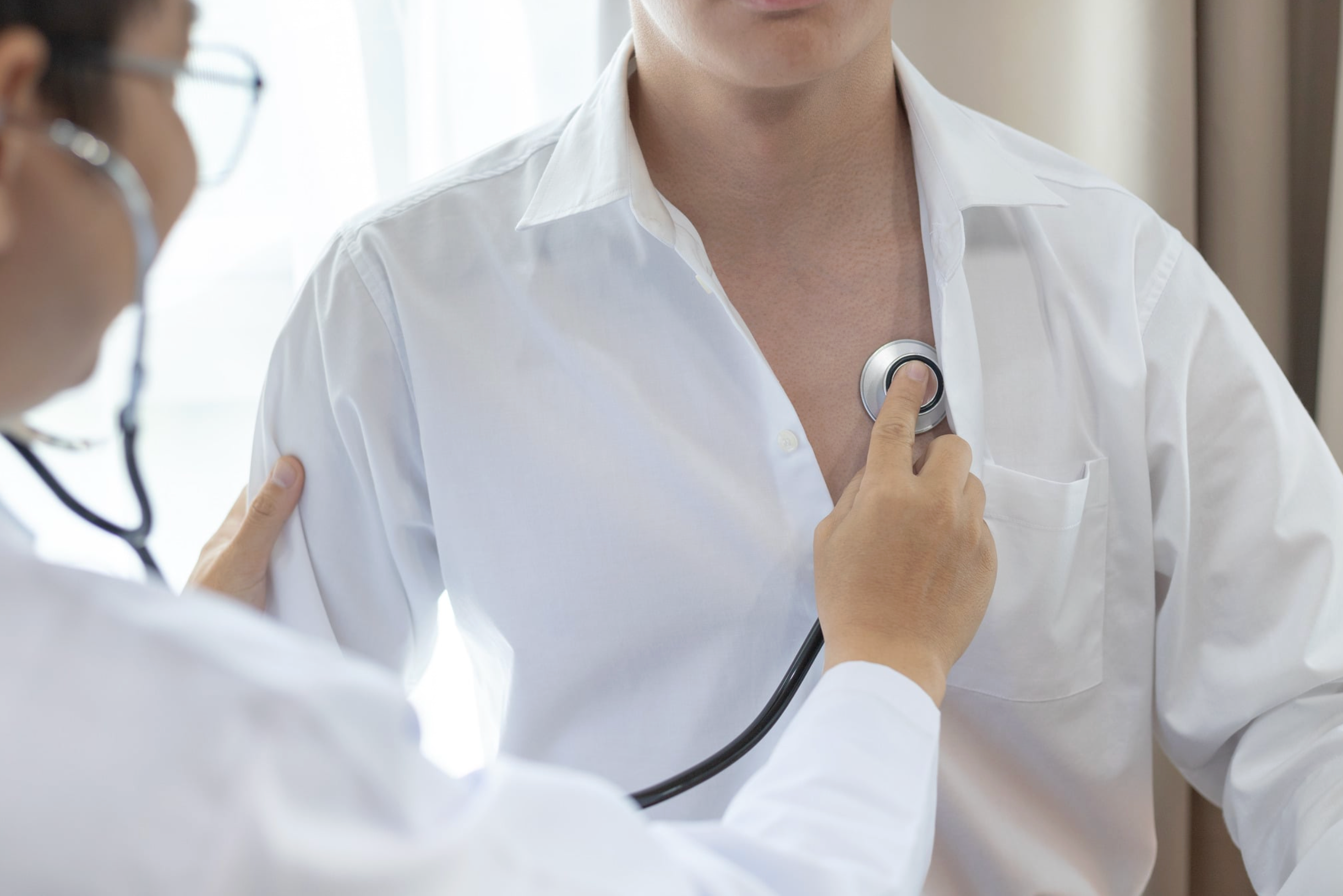 Doctor holding stethoscope up to patients heart