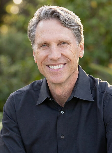 Dr. Murray wearing a dark shirt with a blurred green background