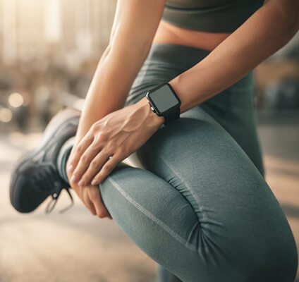 Person wearing a smartwatch and green athletic leggings sitting outdoors.