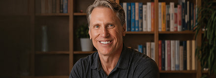 Dr. Murray smiling and wearing a black in front of a bookshelf