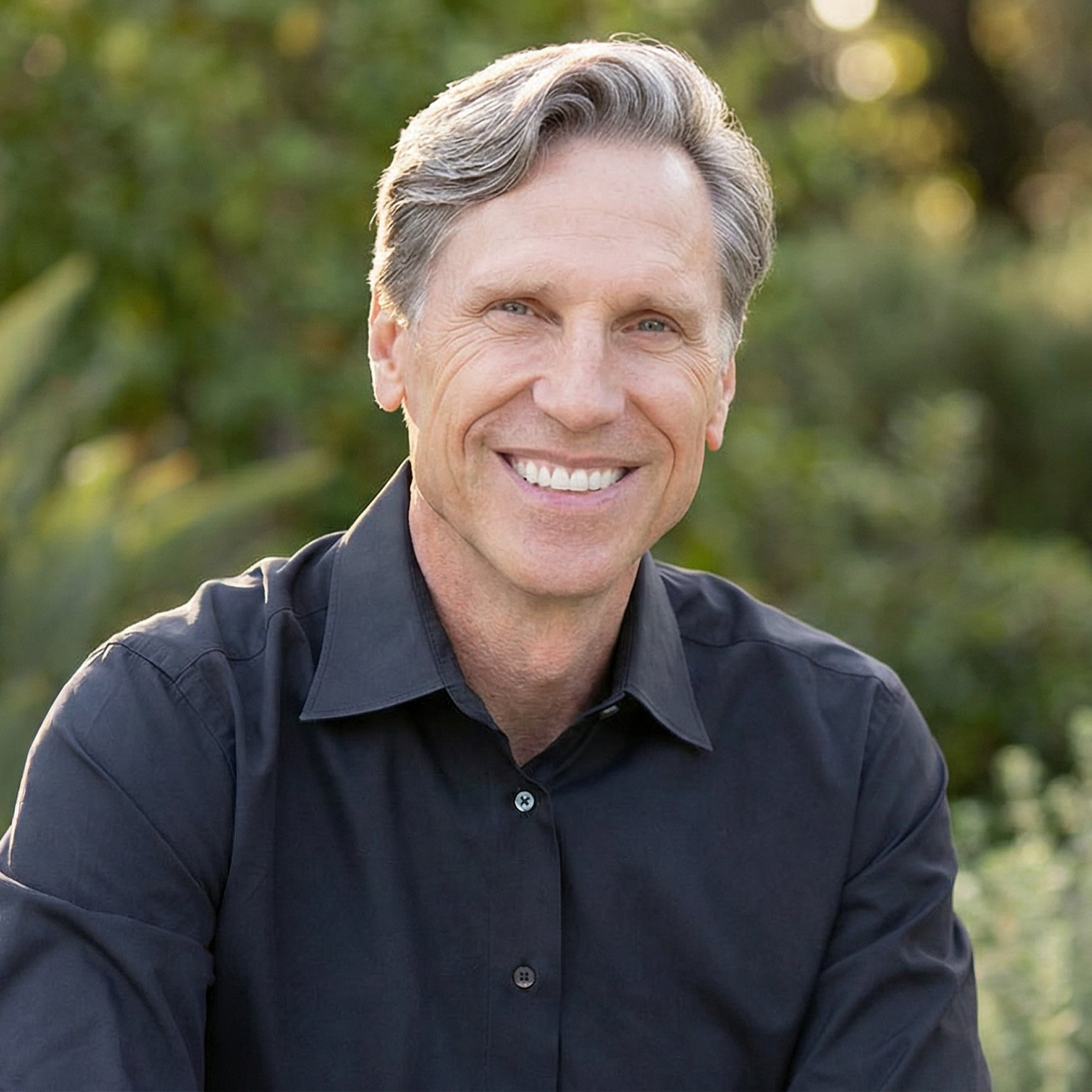 Dr. Murray wearing a dark shirt with a blurred green background