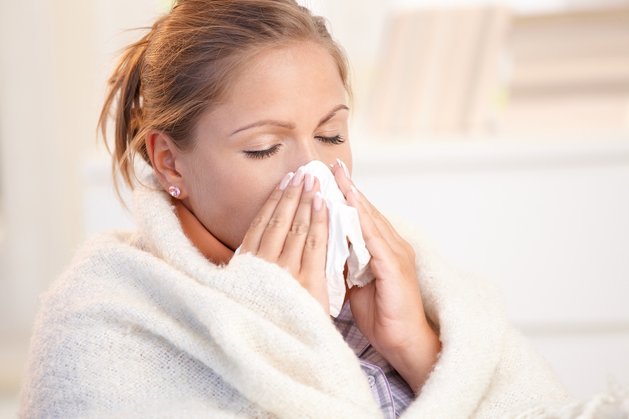 Young woman having flu blowing her nose